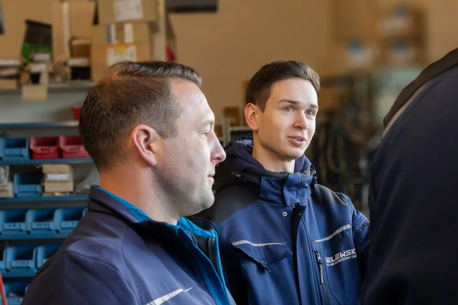 Zwei Kollegen im Gespräch vor Regalen mit Ersatzteilen