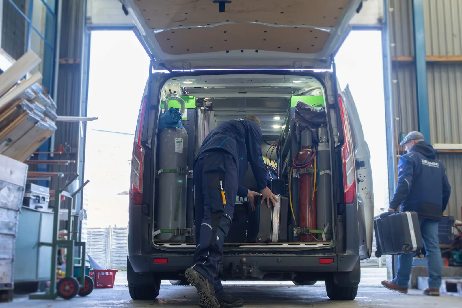 In der Halle wird ein Servicewagen mit Gasflaschen und Werkzeugkoffern beladen